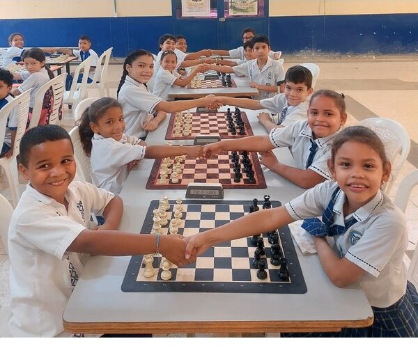 Children greeting each other across chessboards during a Más allá del tablero session
