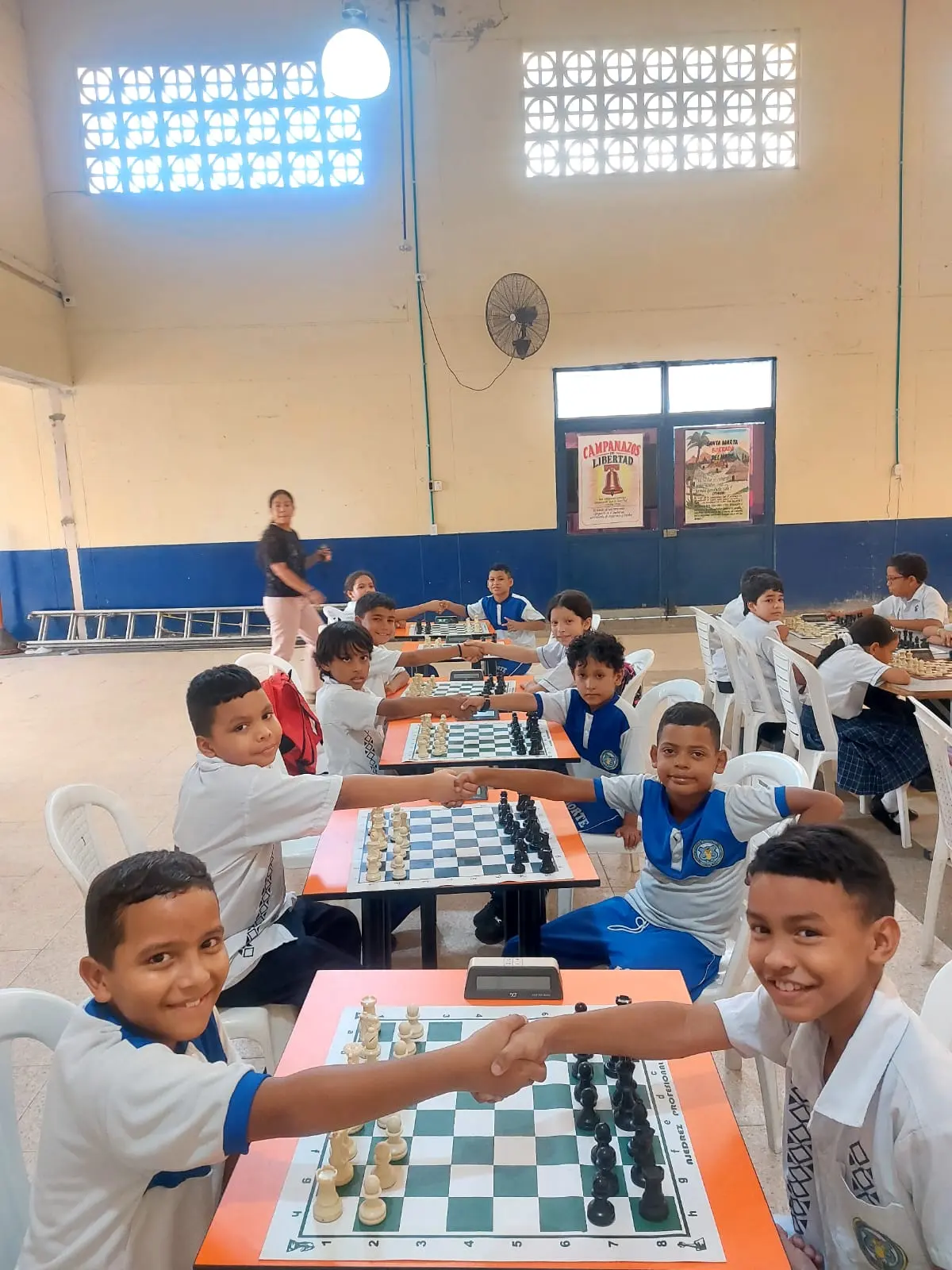 Students greeting one another across chessboards during a school session in Santa Marta