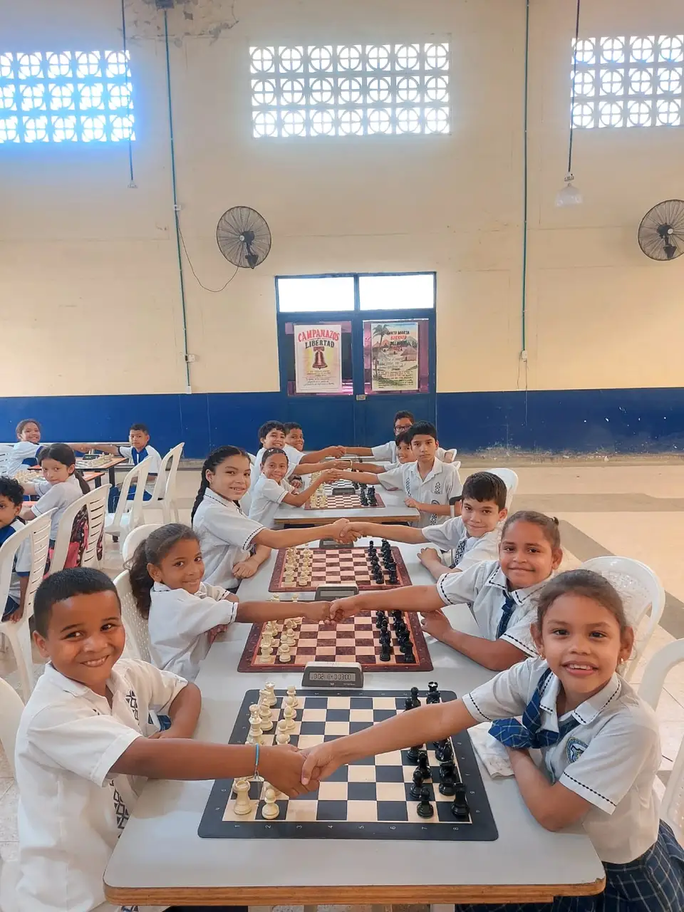 Students smiling together around chessboards during a school session in Santa Marta